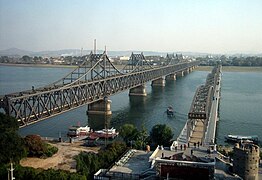 Los dos puentes del Yalu entre Sinŭiju y Dandong. A la izqda., el [puente de la Amistad Sinocoreana]] —abierto en 1943 y destruido por ataques aéreos estadounidenses durante la guerra, pero reparado después de 1953— y a la dcha., el puente roto del río Yalu