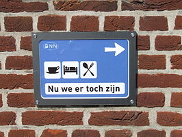 "Nu we er toch zijn" zilveren plaquette aan de muur van het stadhuis te Winterswijk