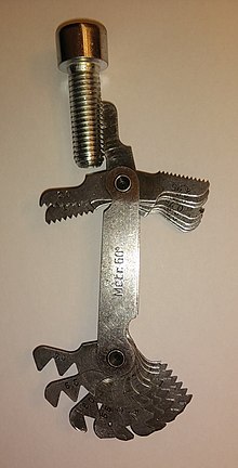 Thread pitch gauge against a screw thread