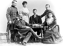 Photographie en noir et blanc montrant quatre hommes en uniforme et deux femmes autour d'une table.