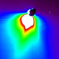 This false-color image shows comet Tempel 1 about 50 minutes after Deep Impact's probe smashed into its surface. The impact site is located on the far side of the comet in this view. The image was taken by the mission's flyby spacecraft as it turned back to face the comet for one last photo opportunity. The colors represent brightness, with white indicating the brightest materials and black showing the faintest materials. This brightness is a measure of reflected sunlight. Because the sunlit portion of the comet is brighter, it appears white. The comet's nucleus is silhouetted against the light reflected from surrounding dust. The large plume of dust that was kicked up upon impact can be seen as the colorful, drop-shaped object. This plume was very bright, indicating that the comet's surface material must be very fine, like talcum powder. The blue speck in the upper left corner is a star. This picture was taken by Deep Impact's high-resolution camera.