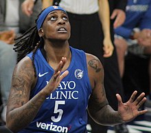 Waist high portrait of young woman wearing navy blue basketball uniform and headband with outstretched hands