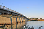 A box girder bridge, with a steel truss railway bridge in the background.