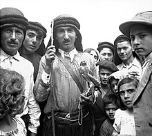 Man holding a falcon, in the centre of a group of people