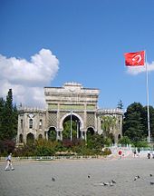 A triumphal arch adjacent to a Turkish flag and in front of an open plaza