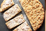 A round streuselkuchen, cut in pieces. Half the cake has been dusted with powdered sugar