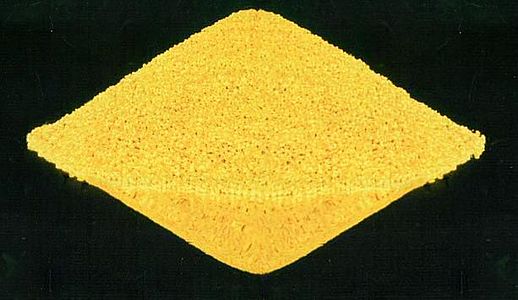 A yellow sand-like rhombic mass on black background.