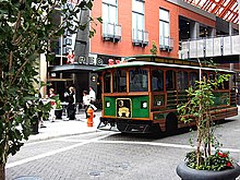 Green-and-brown trolley on a city street