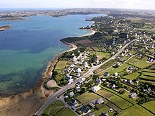 Vue aérienne de maisons en bord de mer, où les constructions modernes sont toutes aux toits d'ardoise bleue et aux murs blancs.