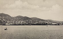 Photographie depuis la mer d'une ville installée entrer mer et montagnes.