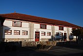 Photographie d’un édifice allongé en quatre parties égales, aux boiseries rouge et à un seul étage.