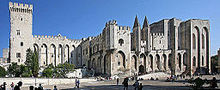 A large robust stone building with one large and two smaller towers