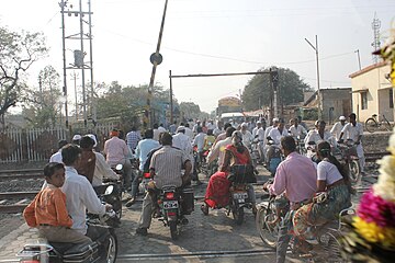 Many motorbikes at a semi-rural railway crossing