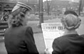 Two young women standing on Saint Catherine Street in Montreal, read the front page of The Montreal Daily Star. The title "Germany Quit" announces the German surrender and the impending end of the World War II.