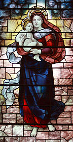 Mary is shown standing holding the baby Jesus high in her arms