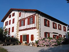 vue de trois quarts d'une maison à deux étages aux pans de bois rouge.