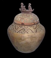 A burial jar with its lid decorated with two people on a boat