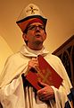 Bishop Brian Prior holding a red book.