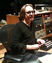 Photo de Butch Vig, le producteur de l'album, assis dans un fauteuil devant du matériel d'enregistrement.