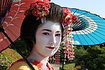 Japansk turist i Kyototradisjonelt utkledd sommaiko, ein geisha-lærling, med kvitsminka ansikt og øvst på ryggen, wareshinobu-frisyre ogkarakasa-paraply