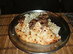 Cevapi em um prato, servido sobre um pão pita.