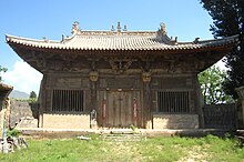 The Main Hall of Yanqing Temple. There is blue sky behind the hall. There is one door opening to a grassy courtyard