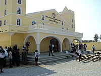 Congregants in their Sunday best outside of a yellow building bearing the church's name