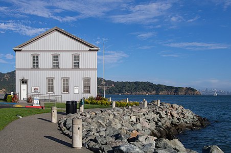 Tiburon Railroad & Ferry Depot Museum in Shoreline Park in Tiburon, California, on San Francisco Bay, with city skyline in the distance.