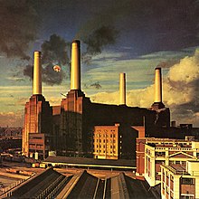 An image of the Battersea Power Station in England, where a giant pig can be seen flying between its left chimneys.