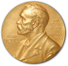 A golden medallion with an embossed image of Alfred Nobel facing left in profile. To the left of the man is the text "ALFR•" then "NOBEL", and on the right, the text (smaller) "NAT•" then "MDCCCXXXIII" above, followed by (smaller) "OB•" then "MDCCCXCVI" below.