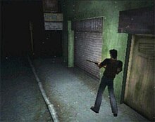 A[liên kết hỏng] video game screenshot that is a digital representation of a dark town street. A man with his back to the viewer holds a rifle as he walks along the side of a green building.