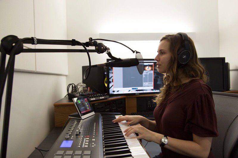 Woman playing piano and singing in a Music Room at the Hunt Library.