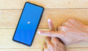 Bangkok, Thailand - 25  August, 2020 : Loading logo of twitter with finger cross sign for anti fake news