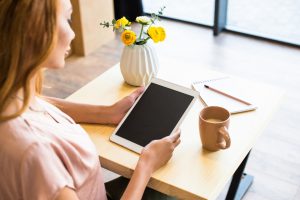 Frau sitzt mit Tablet am Tisch