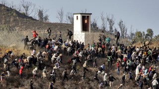 Migrants at the Moroccan town of Fnideq storm a barbed-wire fence as they attempt to cross the land border with Ceuta