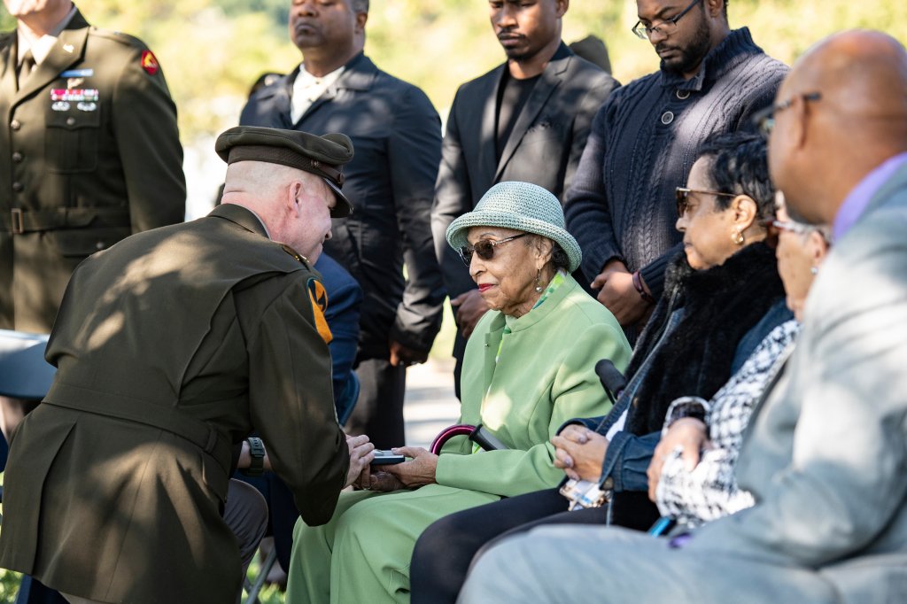 First Army Command Sgt. Maj. Chris Prosser, left, presents JoAnn Woodson, right, with the Bronze Star her husband, U.S. Army Staff Sgt. Waverly Woodson Jr., earned during his service in Section 69 of Arlington National Cemetery, Arlington, Va., Oct. 11, 2023. This medal presentation was part of a ceremony, held near the gravesite of Woodson, to posthumously present JoAnn, Woodson’s wife, with the Bronze Star and the Combat Medic Badge he earned. Staff Sgt. Woodson was a First U.S. Army Soldier and on June 6, 1944, he was part of the first wave of Soldiers who stormed Omaha Beach at Normandy, France during D-Day. Staff Sgt. Woodson was cited for bravery during this event, attending to Soldiers as well as saving wounded men from drowning, all after being wounded himself. These actions earned Staff Sgt. Woodson the Bronze Star and the Combat Medic Badge. Staff Sgt. Woodson was never formally presented the Bronze Star because he left Europe quickly to deploy for Japan. He was just approved for the Combat Medic Badge this past August. (U.S. Army photo by Elizabeth Fraser / Arlington National Cemetery / released)